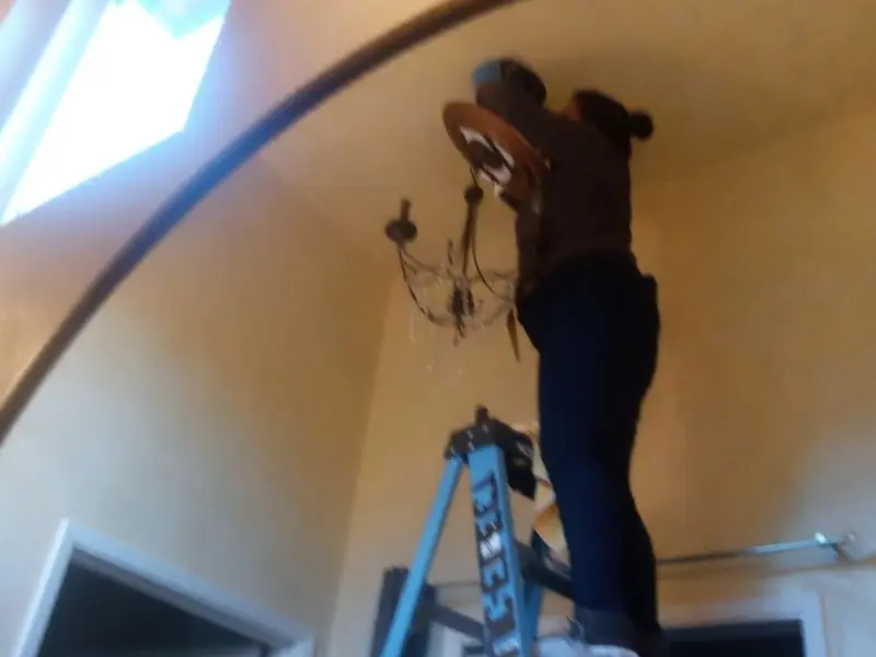 Electrician installing a chandelier in a Lehman residence